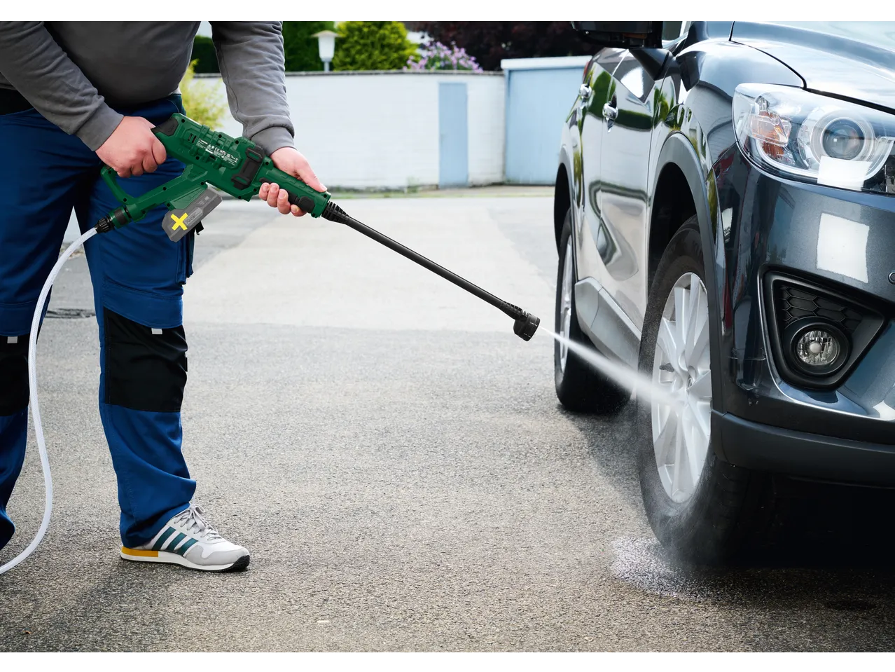Man washing car with a cordless pressure washer.