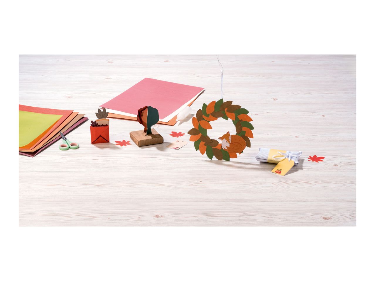 Autumn-themed craft supplies and finished decorations on a wooden table.