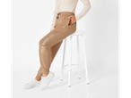 Woman in U.S. Grand Polo brown sweatpants and white sneakers sitting on a stool.