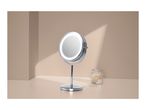 Lighted vanity mirror with cotton buds in a jar and scattered on a beige surface.