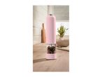 Pink electric pepper grinder with mixed peppercorns on a wooden kitchen counter.