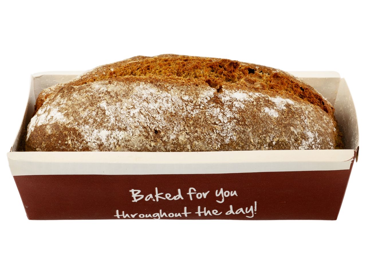 A loaf of dark bread in a brown paper baking pan.