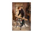 Man working with wood on a workbench in a workshop.