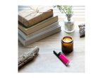 A lit candle, a pink lighter, and a stack of books with a wrapped gift on a wooden table.