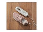 Electric shoe dryer next to a pink sneaker on a wooden floor.