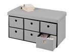 Grey storage ottoman with six fabric drawers, one open showing folded items, and two books on top.