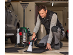 Man cleaning car mats with a Parkside® 1600W Carpet Cleaner in a garage.