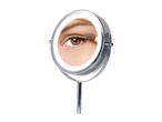 Close-up of a woman's eye in a lighted makeup mirror, applying eyeshadow.