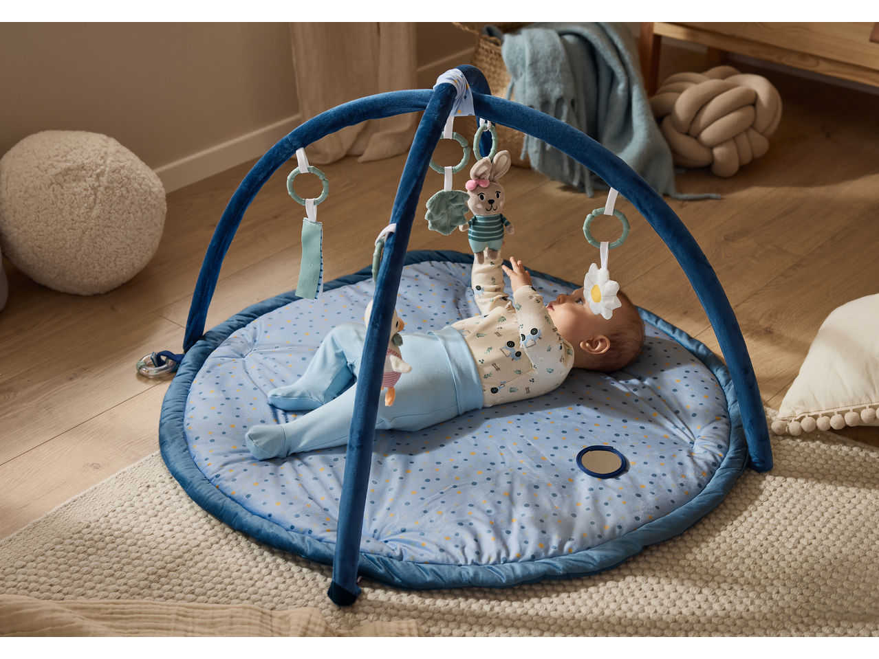 lupilu® Baby Activity Gym with a baby playing with hanging toys on a blue mat.