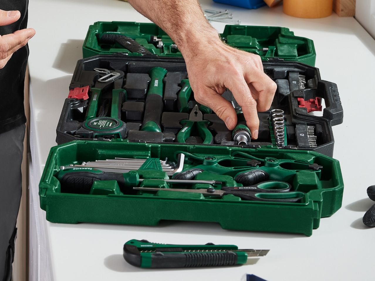 A person organizes Bosch tools in a green carrying case.