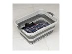 A gray and white collapsible laundry basket sits on a tiled floor, containing folded clothes.