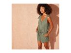Woman in a green linen romper with tie-shoulder straps and a drawstring waist.