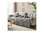 Brown dog resting on a grey fluffy pet sofa bed on a light grey sofa in a living room.