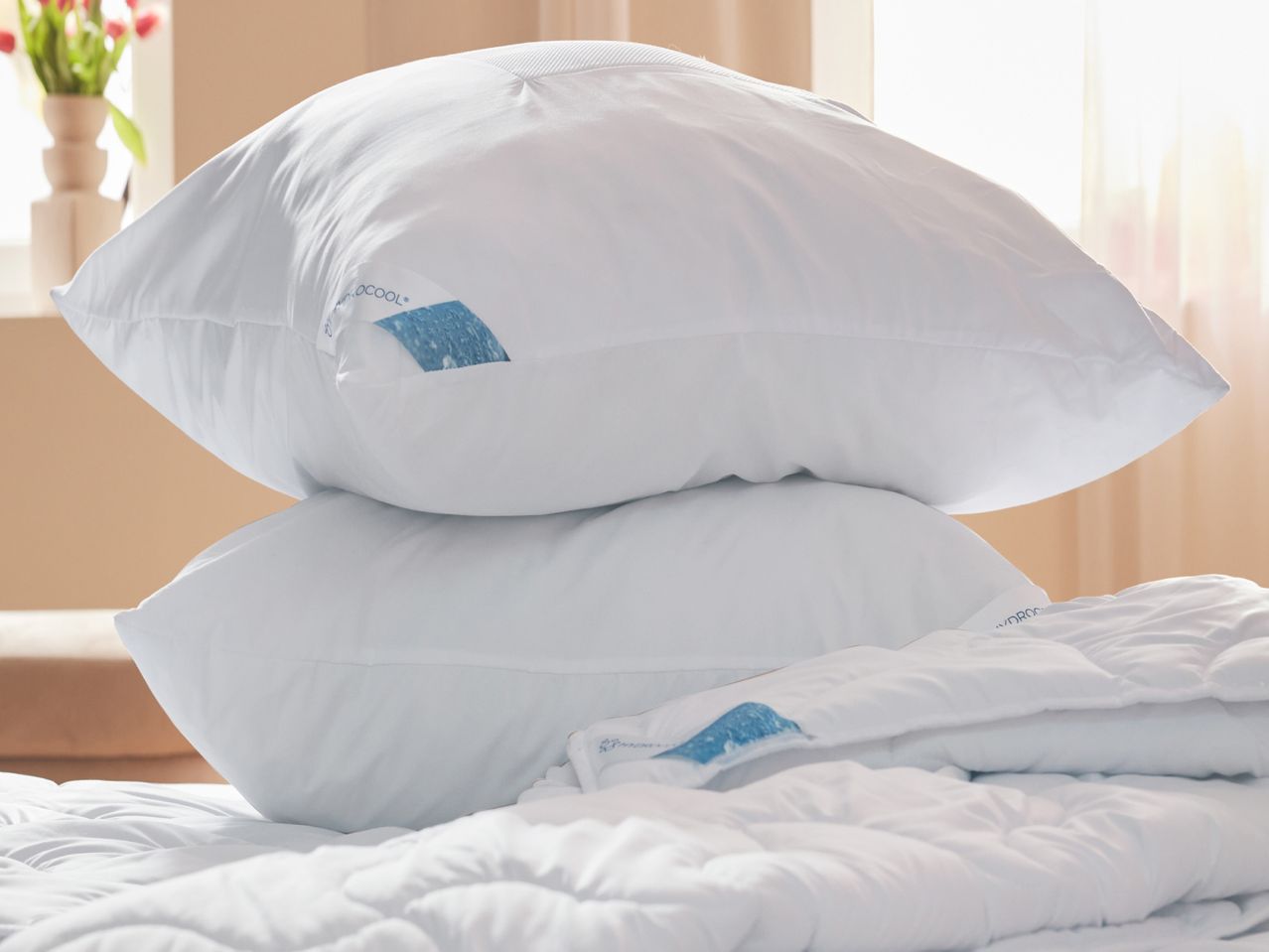 Two white pillows stacked on a bed, possibly hotel-style.