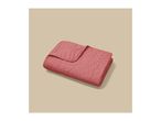 Folded pink quilted blanket with a geometric pattern on a beige background.