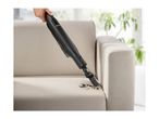 Handheld vacuum cleaner being used to clean dirt from a beige sofa.