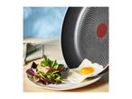 Fried egg sliding from a non-stick pan onto a plate with fresh salad.