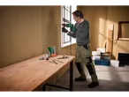 Man drilling into wall with Parkside rotary hammer, tools on table.