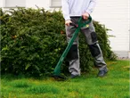 A man uses a Parkside grass trimmer to cut the grass.