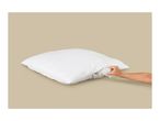 A hand adjusting the filling of a white pillow with a zipper.