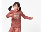 Menina com moletom rosa e saia de lantejoulas.