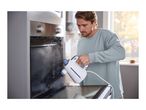 Man cleaning an oven with a handheld steam cleaner, steam visible inside the oven.