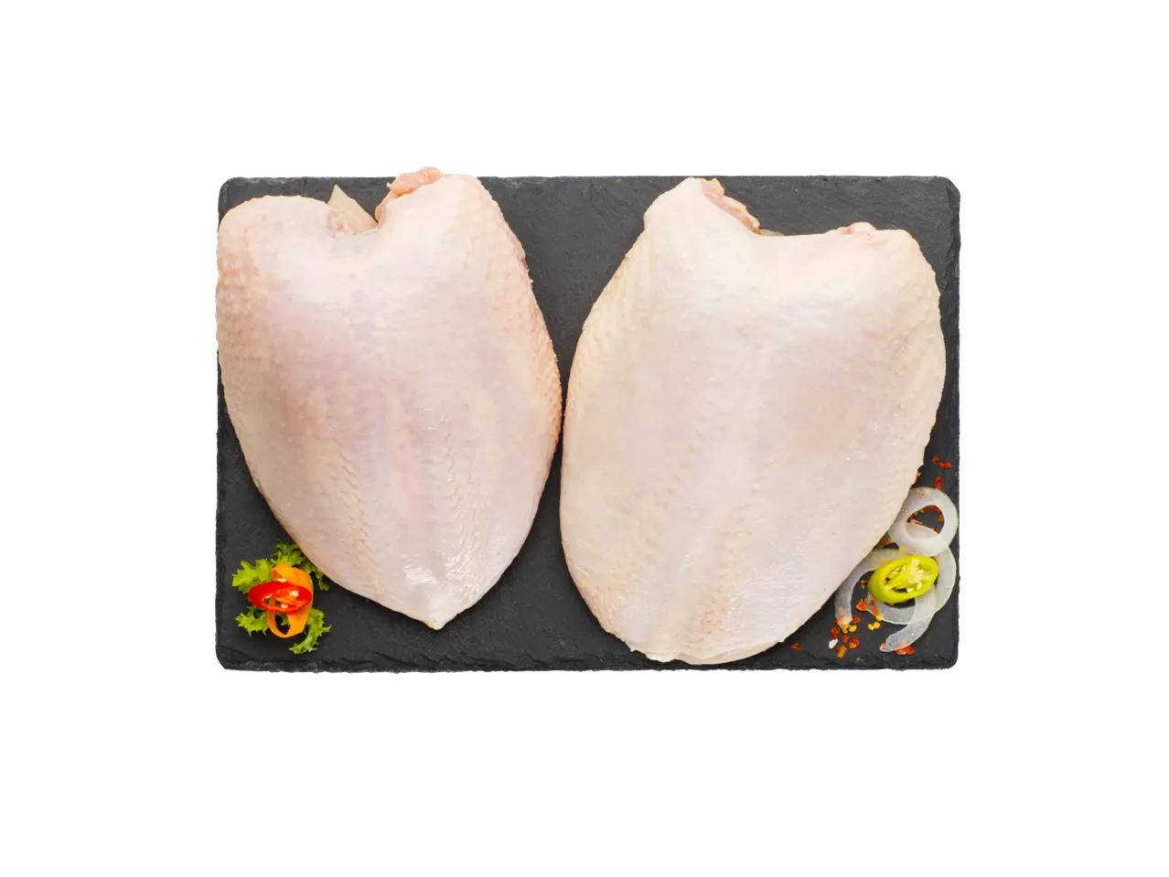 Dva sirova pileća filea na crnoj ploči sa začinima i povrćem.