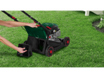 A person assembles an Einhell lawnmower on the grass.