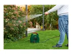 A person watering plants with a garden hose reel in a lush green garden.