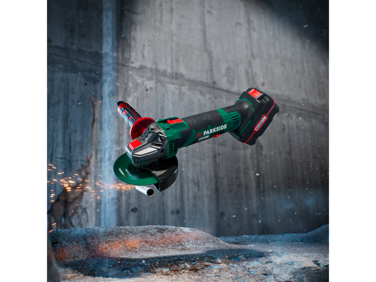 Cordless angle grinder with sparks flying, cutting a metal pipe in a concrete setting.