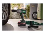 Cordless impact wrench with battery pack, sockets and a car wheel in the background.