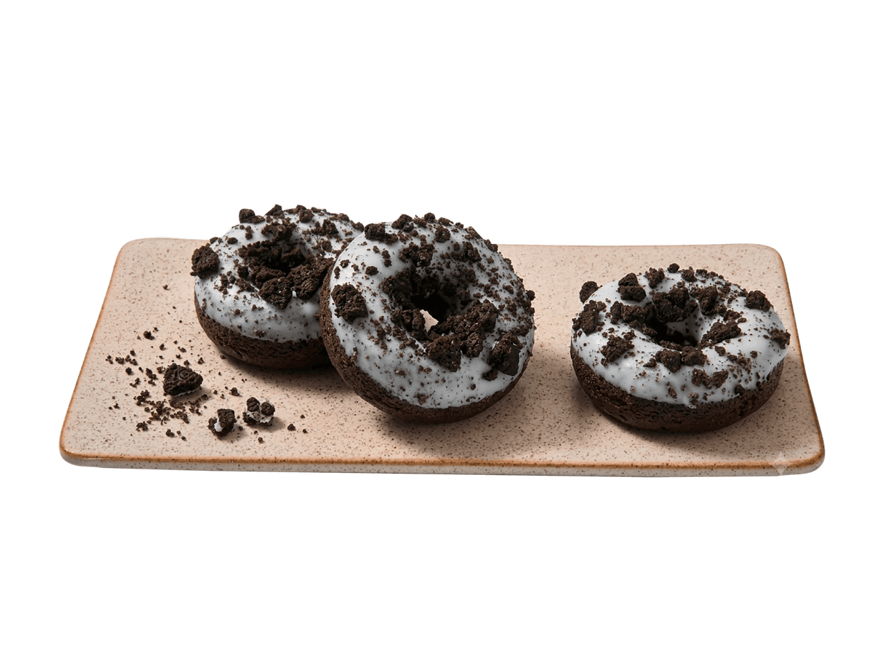 Trois donuts au chocolat avec glaçage blanc et morceaux de biscuits sur un plateau rectangulaire.