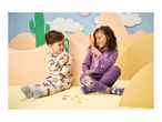 Two children in pajamas playing with magnifying glasses and toy insects.