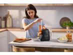 Mulher na cozinha usando um ralador elétrico de vegetais SILVERCREST para ralar cenouras.