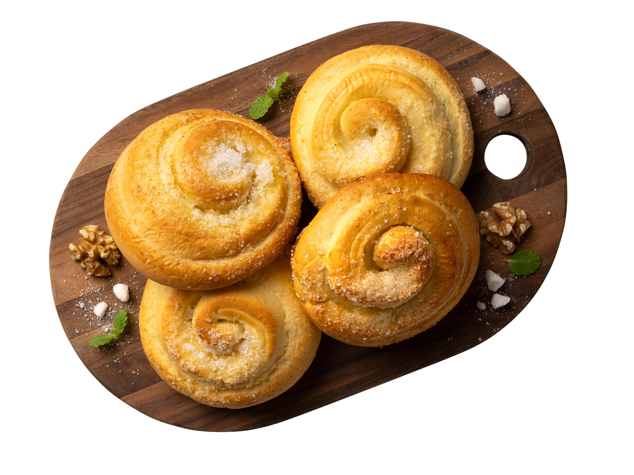 Négy aranybarna, cukros csiga sütemény egy fa vágódeszkán, dióval és mentával díszítve.