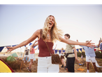 Atmosferă de festival: tânără cu pantaloni scurți și geantă, înconjurată de prieteni și corturi.