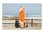 Orange paddleboard set with accessories on a sandy beach