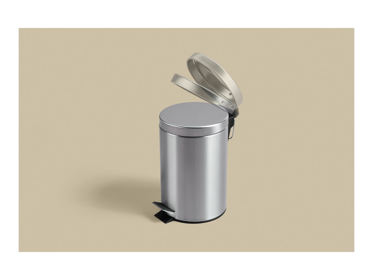 Silver stainless steel pedal bin with the lid open on a beige background.