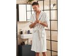 Man wearing a striped white bathrobe in a bathroom.