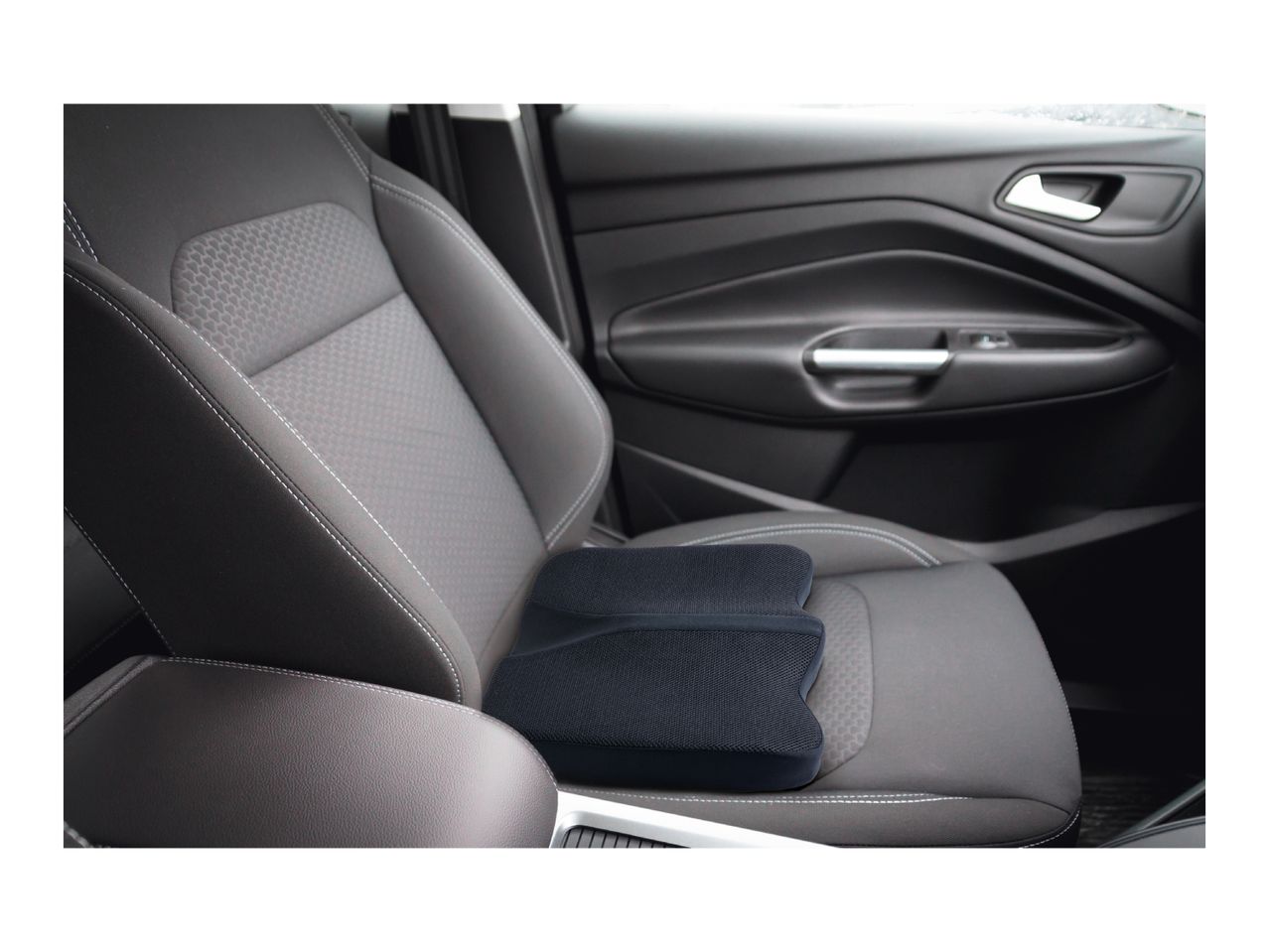 Black car seat cushion on a grey car seat with white stitching.