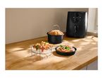 Air fryer with various accessories: a cake in a pot, skewers on a rack, and a pizza.