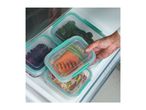 A hand placing a plastic food storage container with salmon and vegetables into a refrigerator.