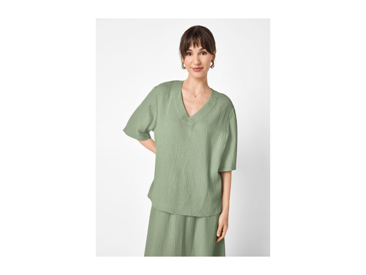 Woman in a sage green textured V-neck top and matching skirt