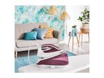 Steam generator iron on an ironing board in a living room with a sofa and plants.