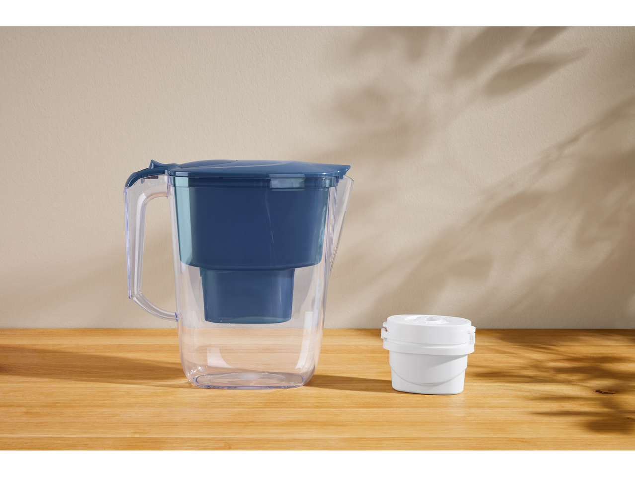 Set de filtrare a apei SILVERCREST® cu cană și filtru pe o masă de lemn.
