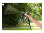Hand holding a green garden spray gun watering plants in a garden