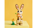 A toy bunny holding a carrot, with a small flower next to it, on a yellow background.