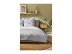 A bedroom with a bed featuring floral pillows and a quilted duvet, a wooden nightstand, and a shelf with decor.