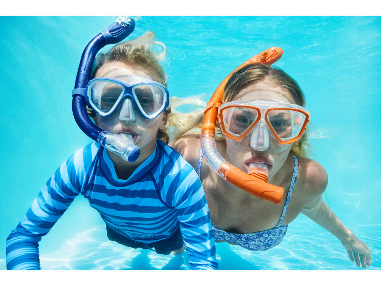 Două persoane fac snorkeling cu măști și tuburi Crivit într-o piscină.