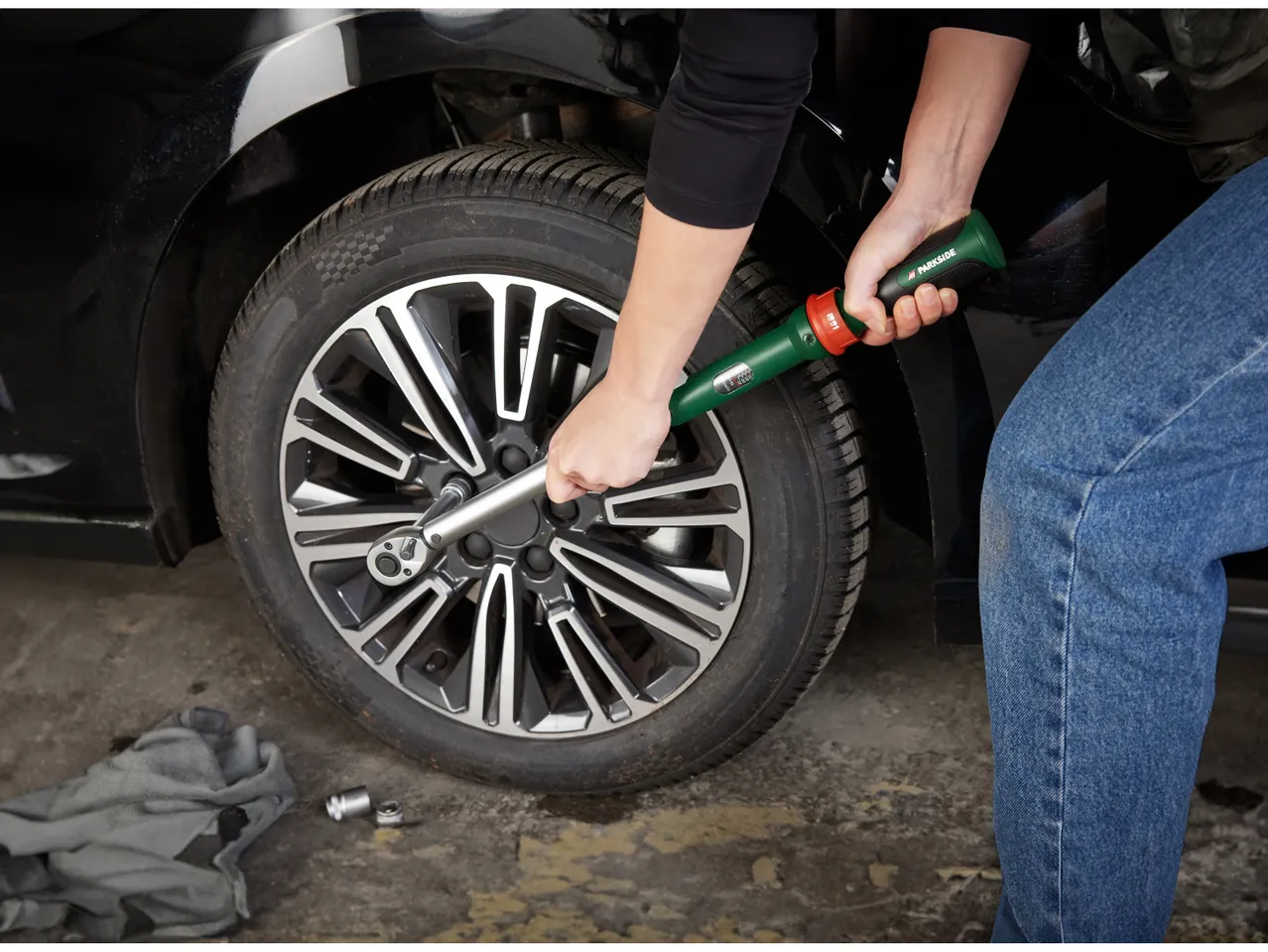 Una persona usa una chiave dinamometrica per stringere i dadi di una ruota d'auto.